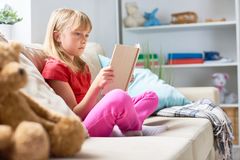 wrapped-up-reading-profile-view-pretty-little-girl-sitting-lotus-position-couch-adventure-story-interior-cozy-100068057.jpg